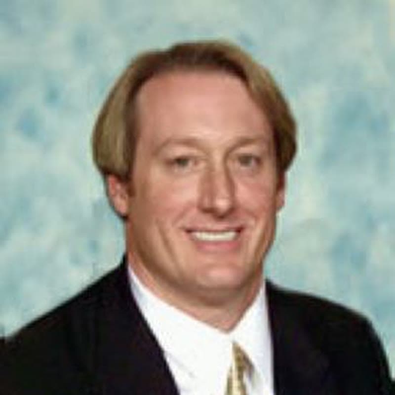 Dr. Gene Boyle of Berkshire Hathaway HomeServices Nevada Properties, wearing a dark suit and gold tie