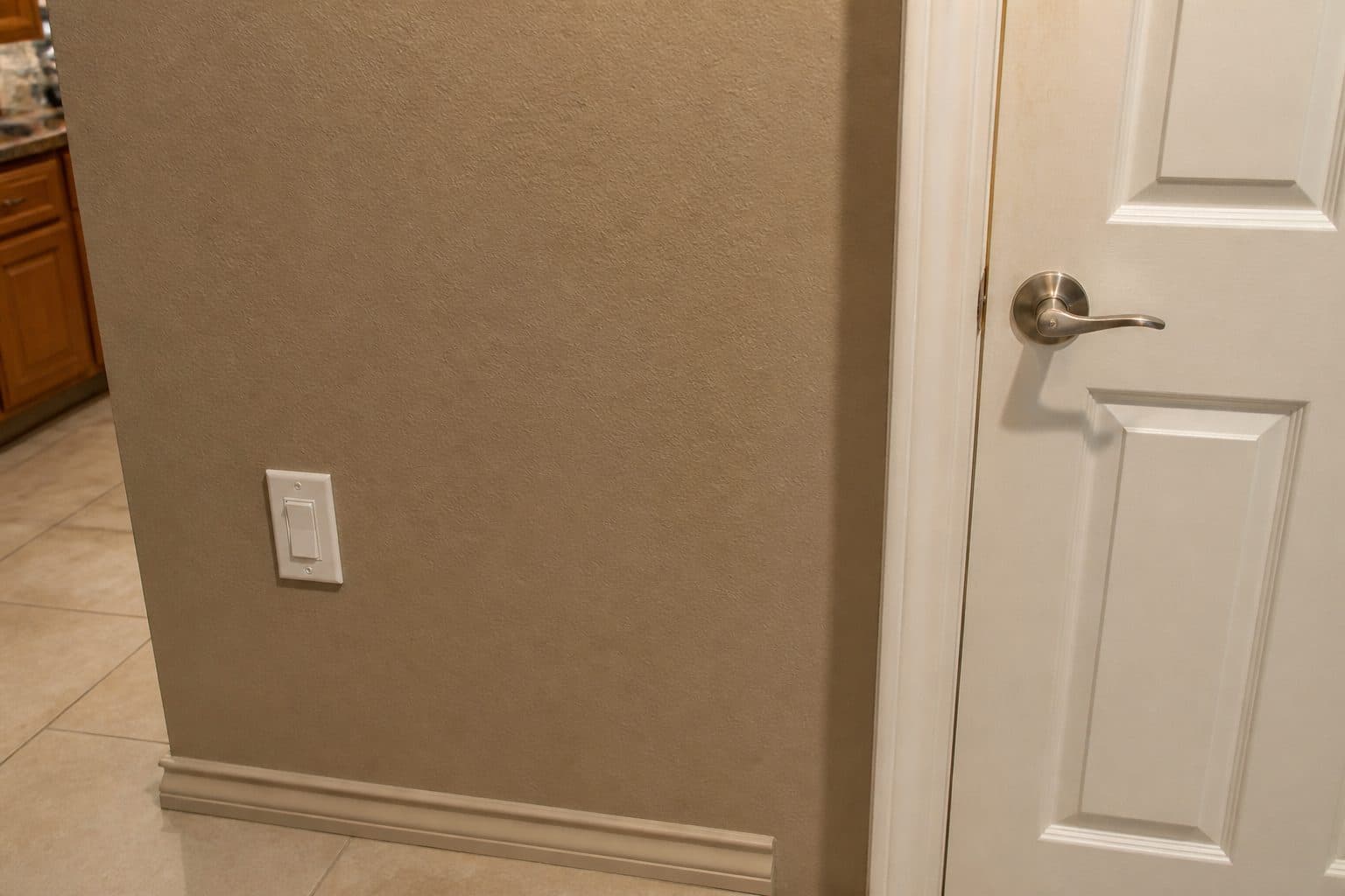 Close-up of a lever door handle and a light switch at a seated reach height.