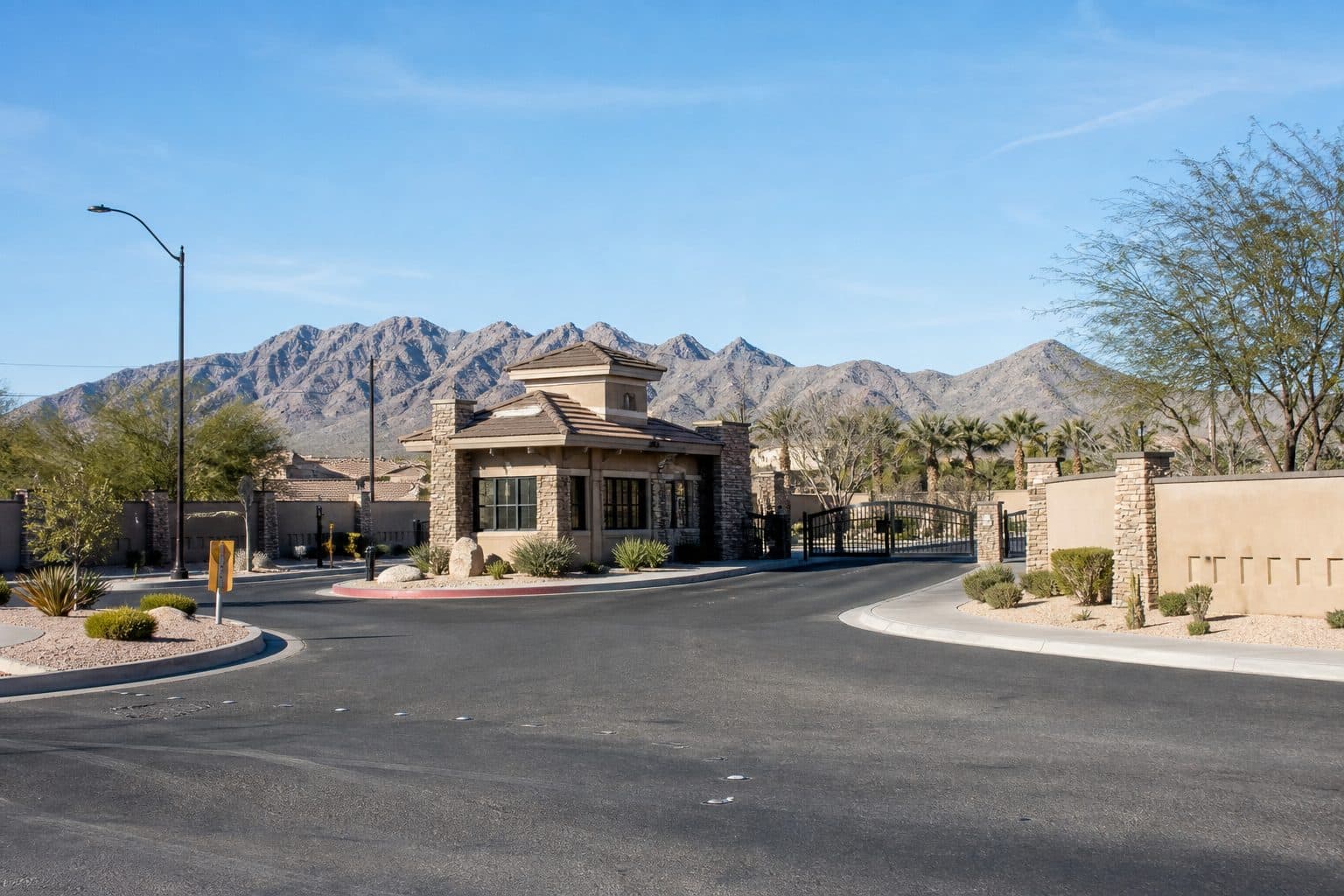 Staffed vehicle gatehouse at a Henderson community entrance, mountains beyond the wall.