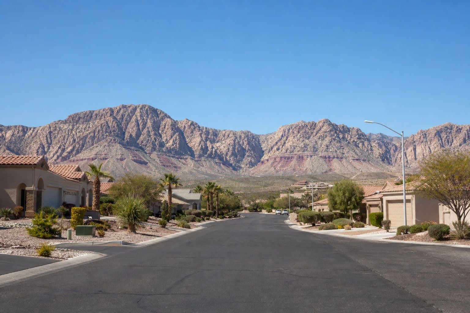 Northwest Las Vegas single-level homes on a wide street, Red Rock range in the distance.