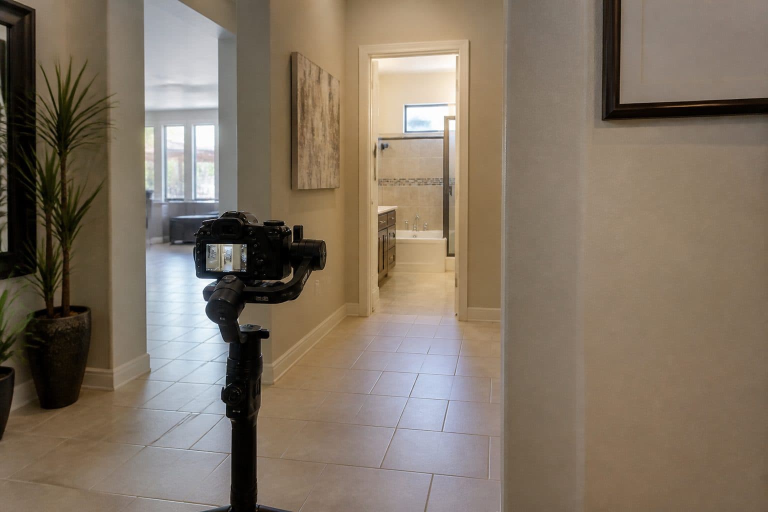 Gimbal camera pointed down a residential hallway toward a bathroom doorway.