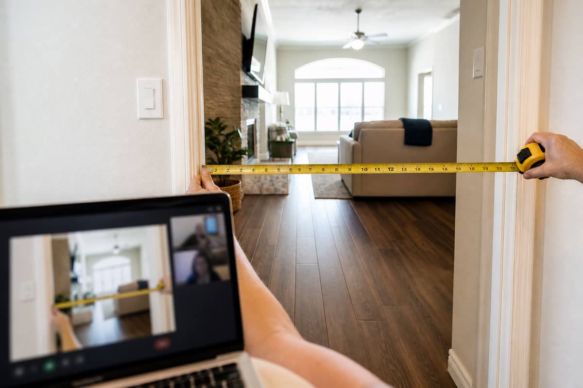 Tape measure on a door jamb while a laptop shows the same doorway on a video call.