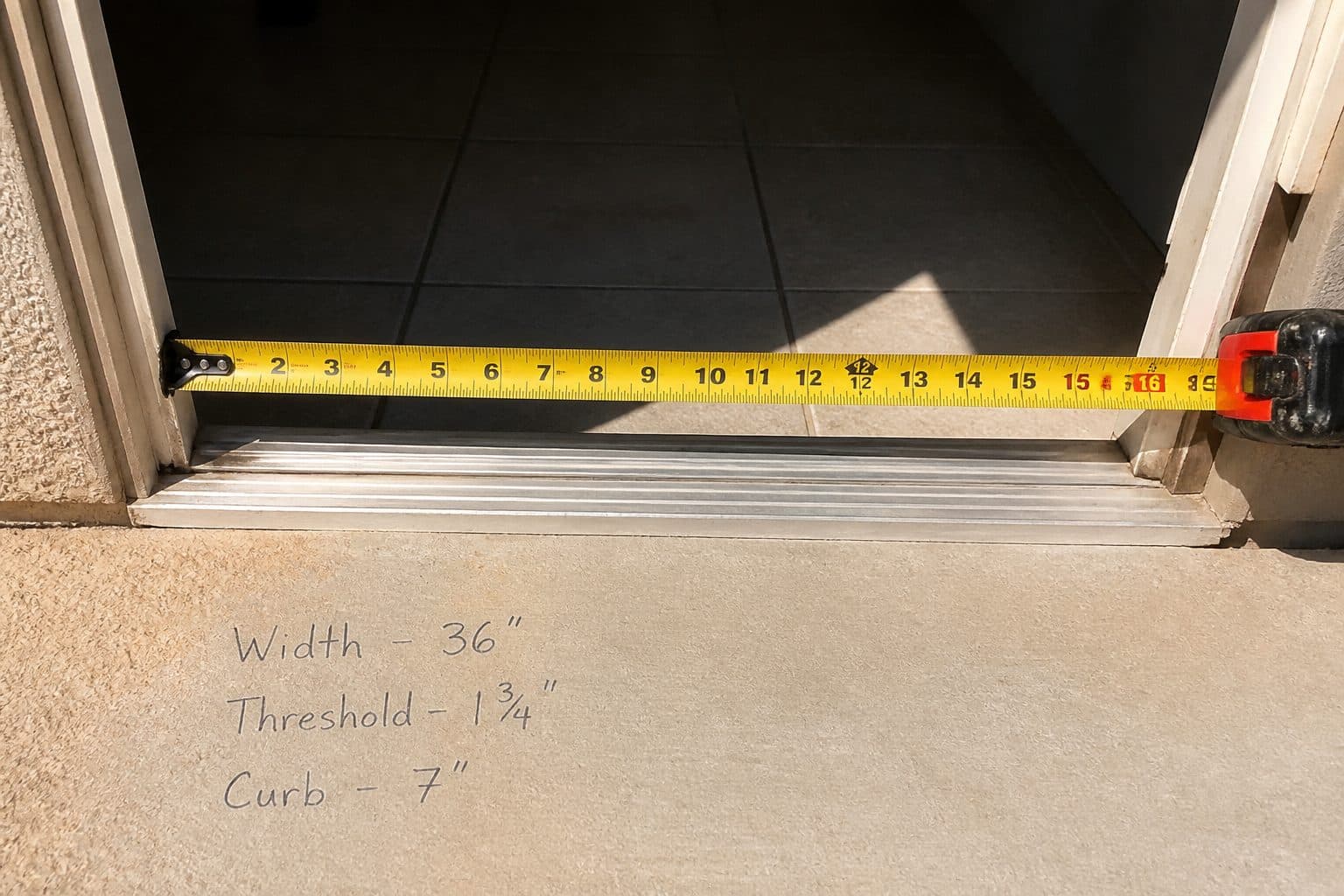 Tape measure reading door clear width; handwritten notes say width, threshold, curb.